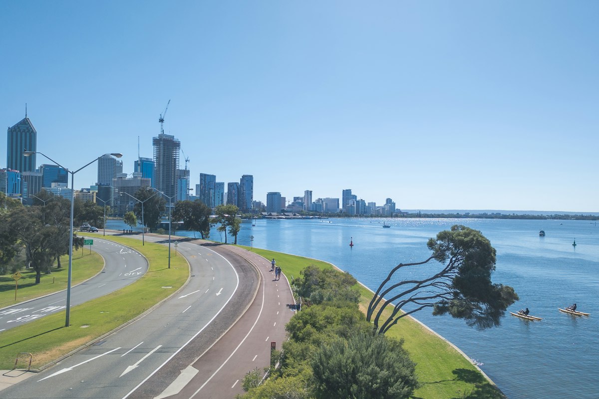 Swan River foreshore path and kayaks with the Perth skyline beyond