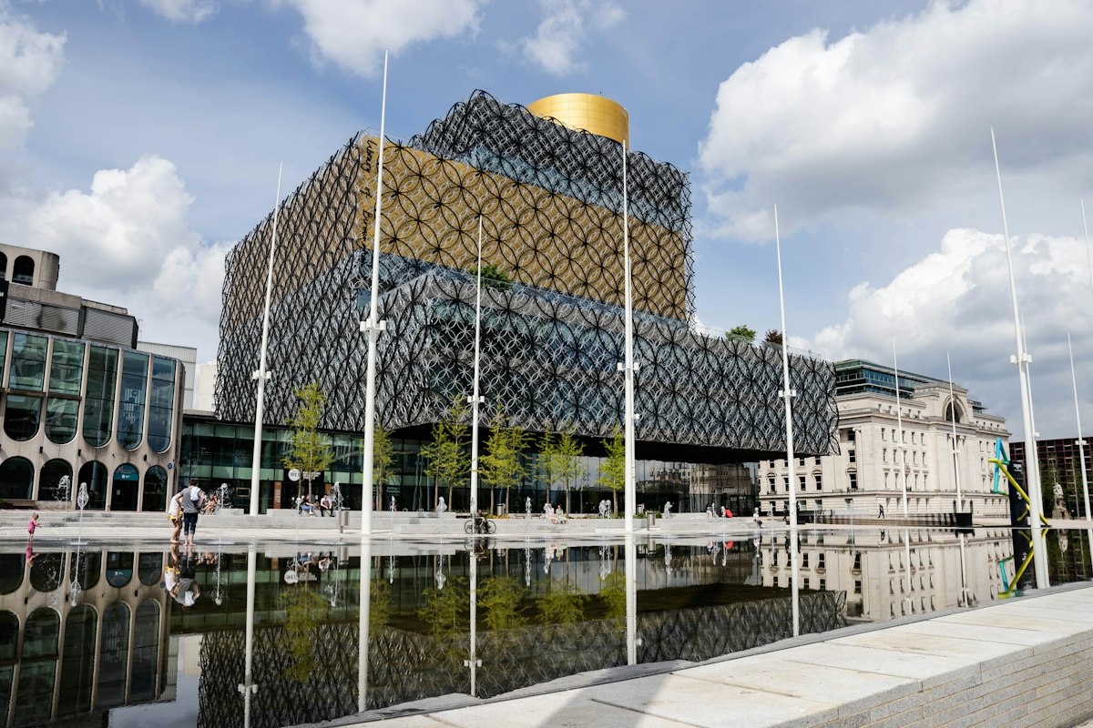 Library of Birmingham reflecting in Centenary Square pool under blue sky