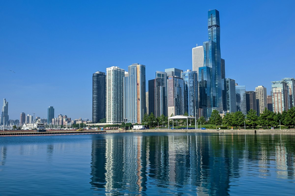 Chicago skyline reflecting in Lake Michigan under a clear blue sky